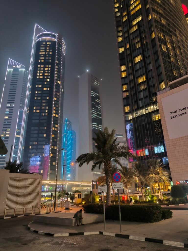 Tall buildings in Doha lighting up at night.