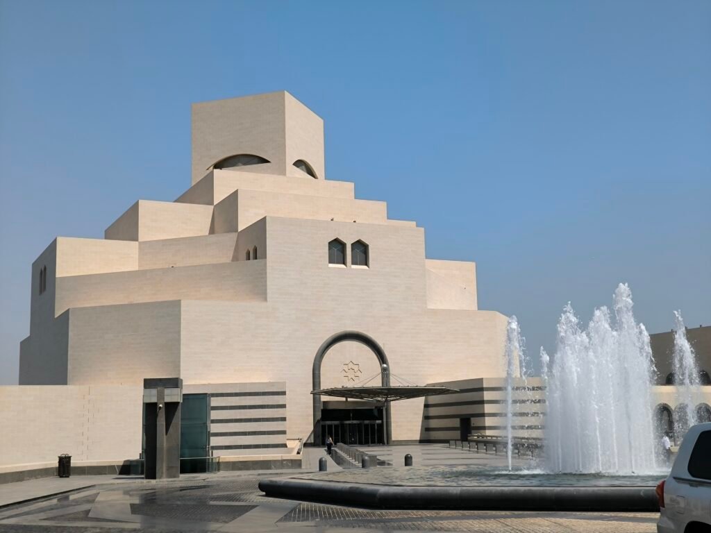 The Museum of Islamic arts featuring a cubic design and a fountain in front.