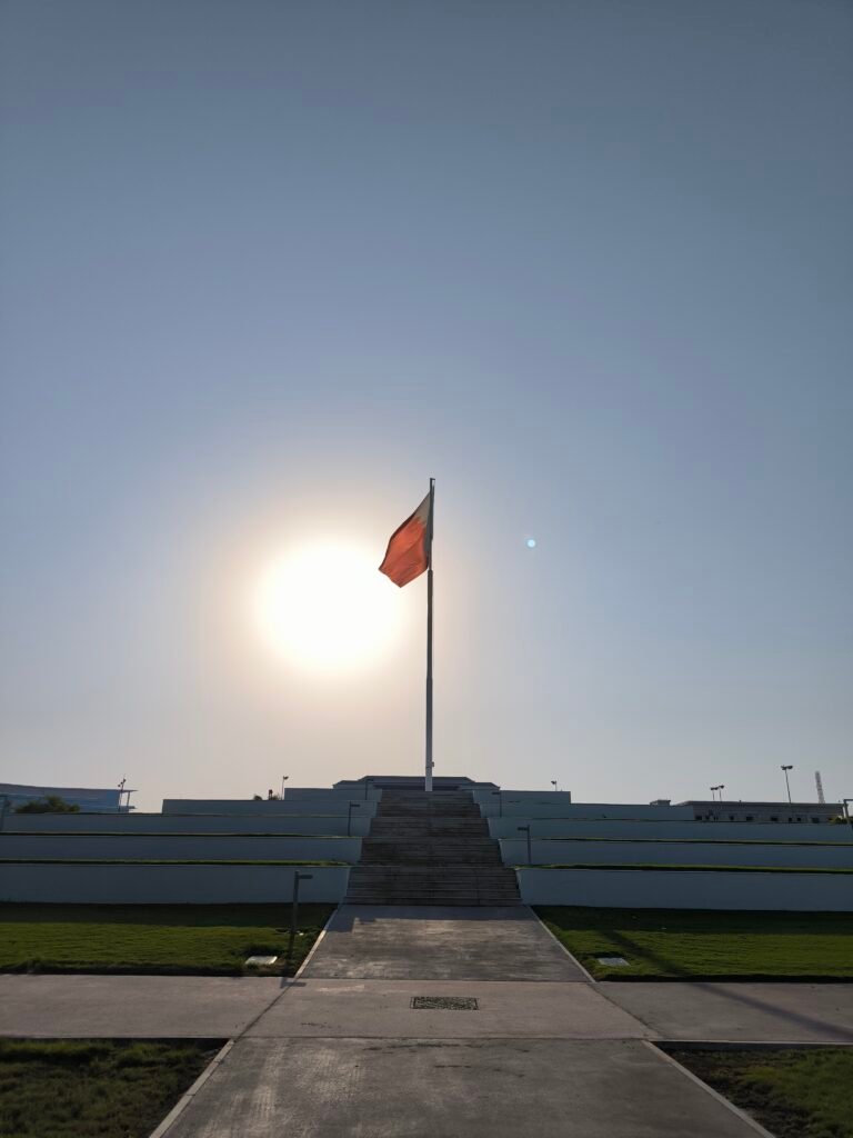 Qatar's National Flag waving in the wind, with the setting sun in the background.